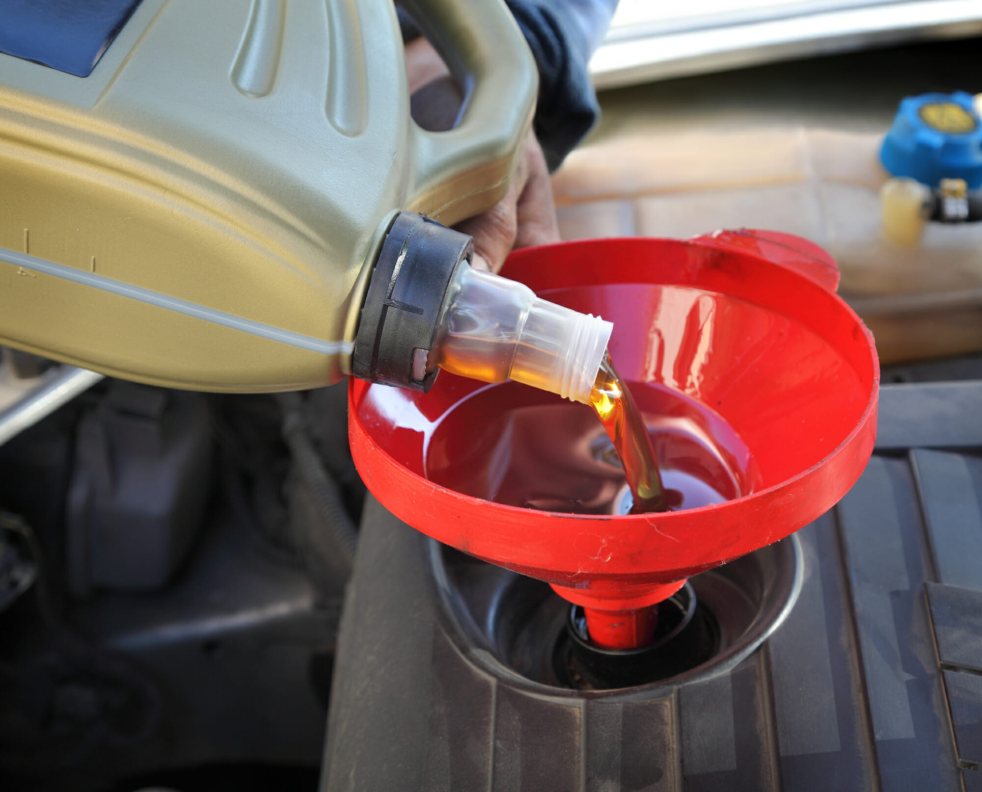 Mecánico de automóviles vertiendo un aceite