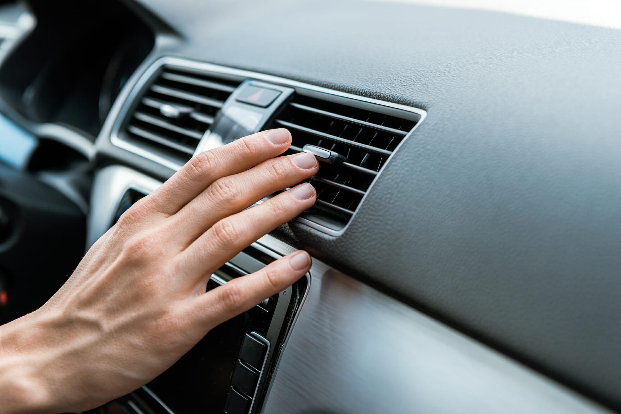 Conductor que revisa el aire acondicionado del automóvil