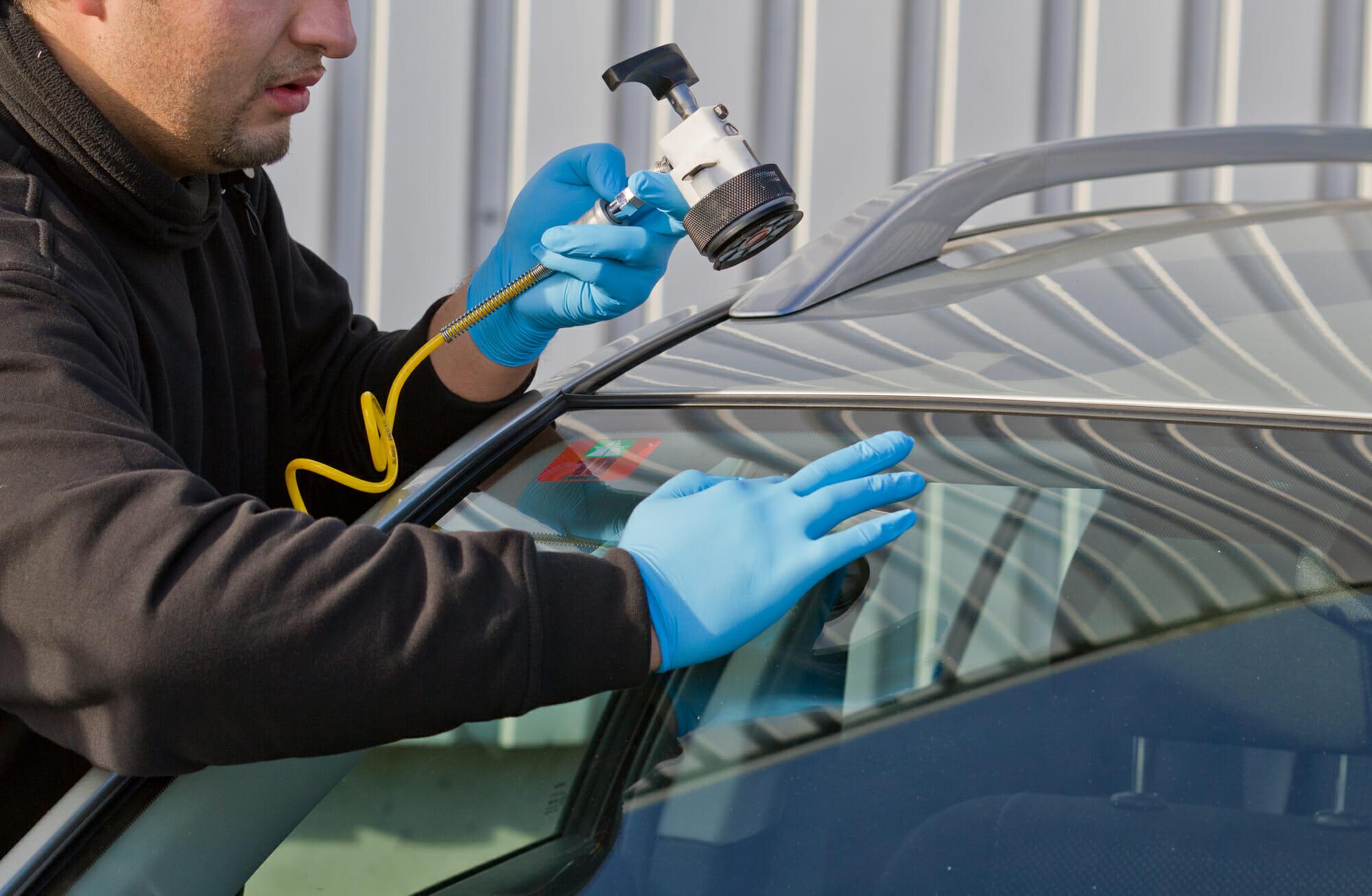 Hombre reparando el parabrisas agrietado del coche