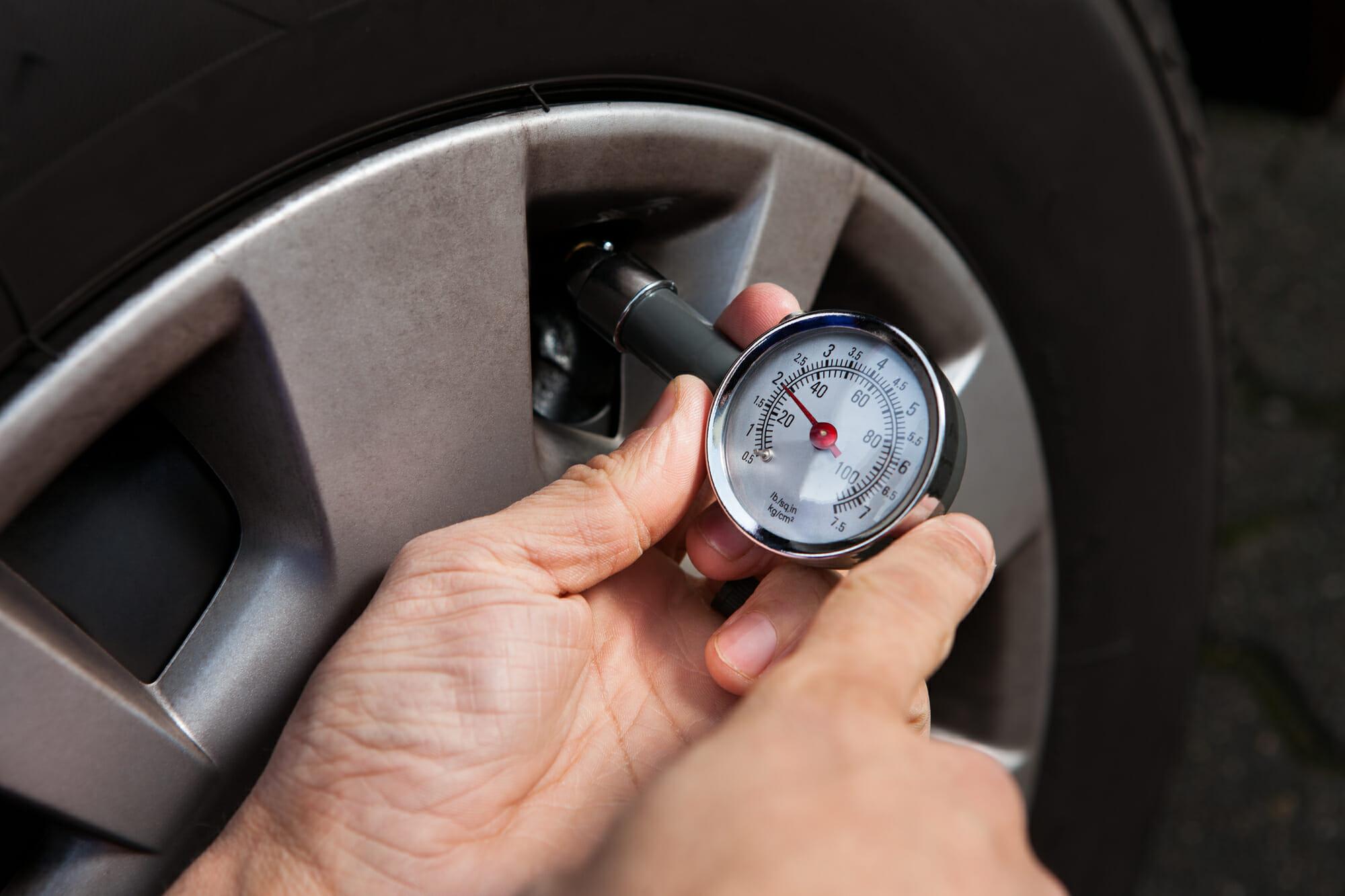 Mecánico de automóviles que comprueba la presión de los neumáticos